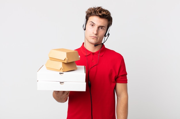 Young handsome man feeling puzzled and confused. take away fast food concept