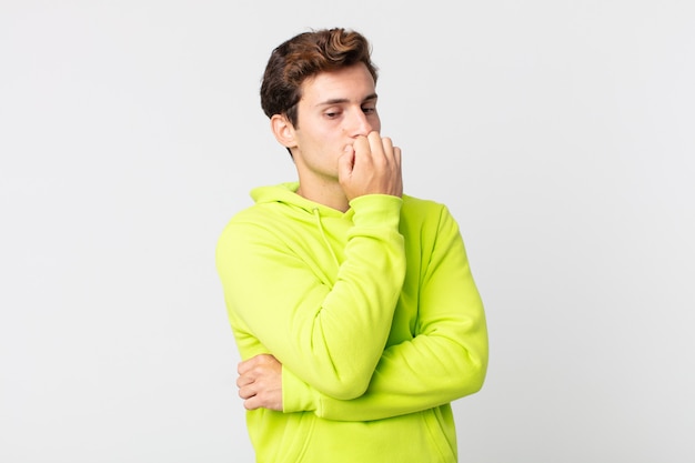 Young handsome man feeling serious, thoughtful and concerned, staring sideways with hand pressed against chin