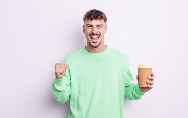 Young handsome man feeling shocked,laughing and celebrating success. take away coffee concept