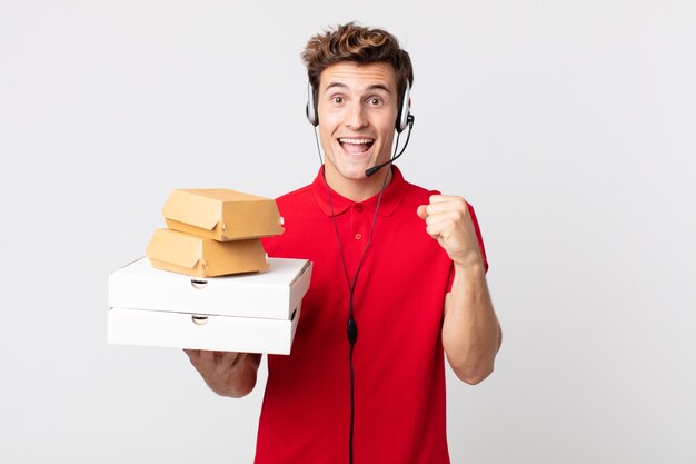 Young handsome man feeling shocked,laughing and celebrating success. take away fast food concept