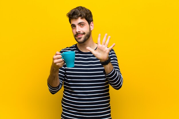 Young handsome man having a coffee against orange