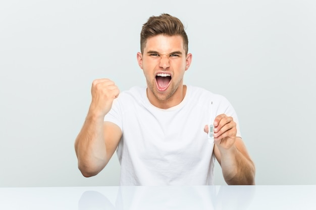 Young handsome man holding armometer cheering carefree and excited. Victory .