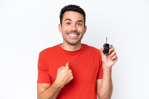 Young handsome man holding car keys over isolated white background with surprise facial expression