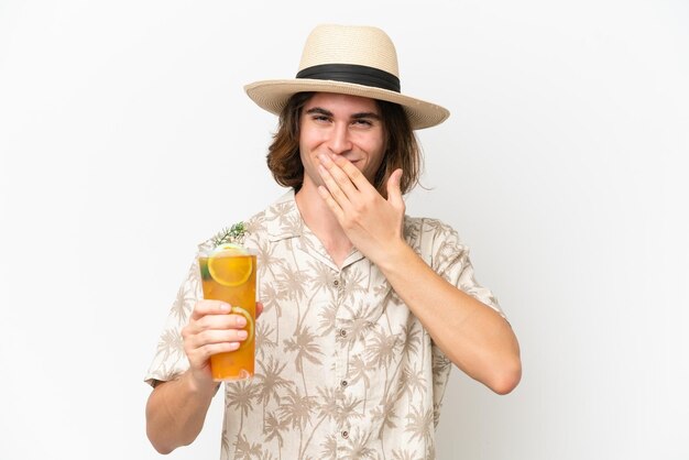 Young handsome man holding a cocktail isolated on white background happy and smiling covering mouth with hand