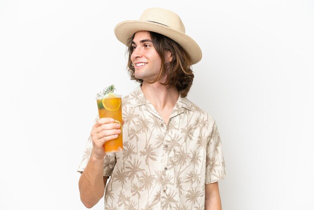 Young handsome man holding a cocktail isolated on white background looking side