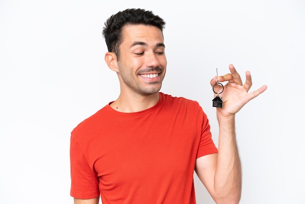 Young handsome man holding home keys isolated over isolated white background with happy expression