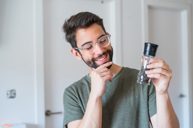 Young handsome man holding pepper at home