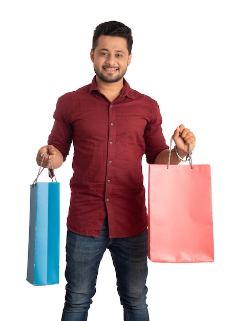 Young handsome man holding and posing with shopping bags on a white background