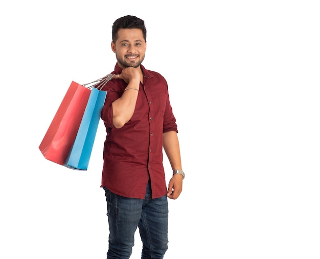 Young handsome man holding and posing with shopping bags on a white background