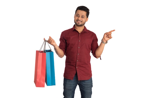 Young handsome man holding and posing with shopping bags on a white background