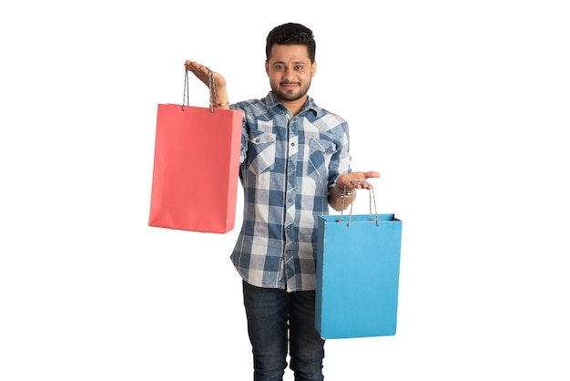 Young handsome man holding and posing with shopping bags on a white background