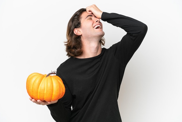 Young handsome man holding a pumpkin isolated on white background smiling a lot