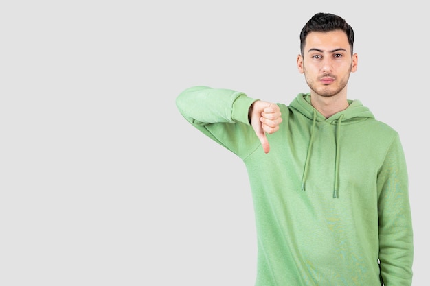 young handsome man in hoodie standing and giving thumbs down