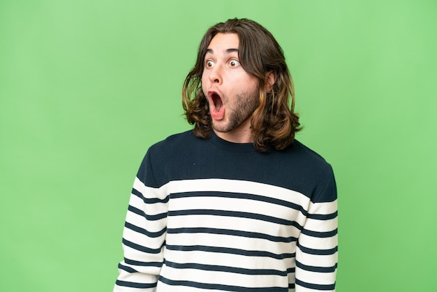 Young handsome man over isolated background doing surprise gesture while looking to the side