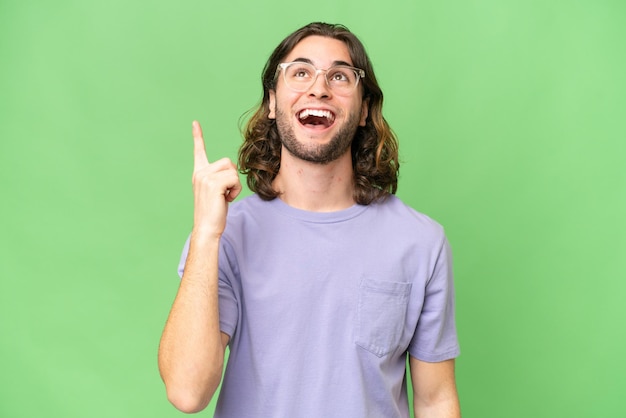 Young handsome man over isolated background pointing up and surprised