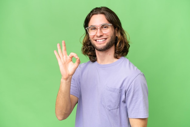 Young handsome man over isolated background showing ok sign with fingers