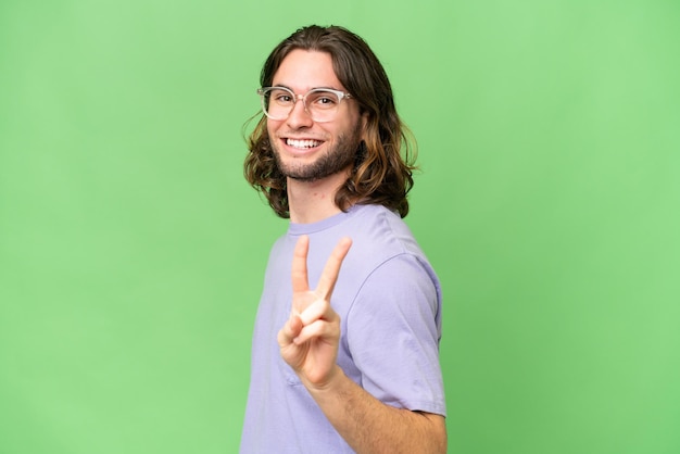 Young handsome man over isolated background smiling and showing victory sign