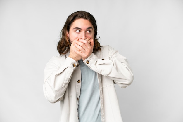 Young handsome man over isolated white background covering mouth and looking to the side