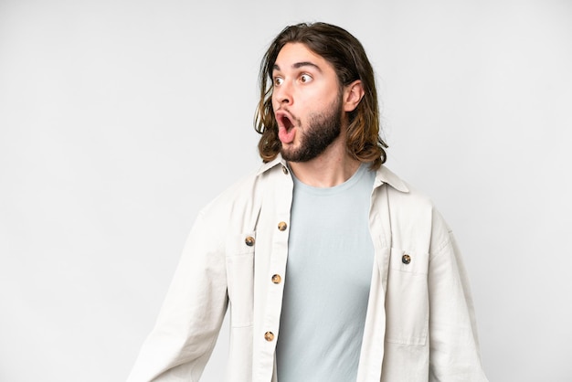 Young handsome man over isolated white background doing surprise gesture while looking to the side