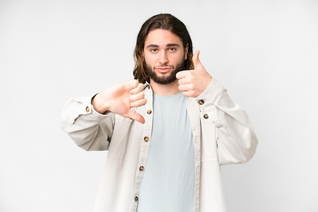 Young handsome man over isolated white background making goodbad sign Undecided between yes or not