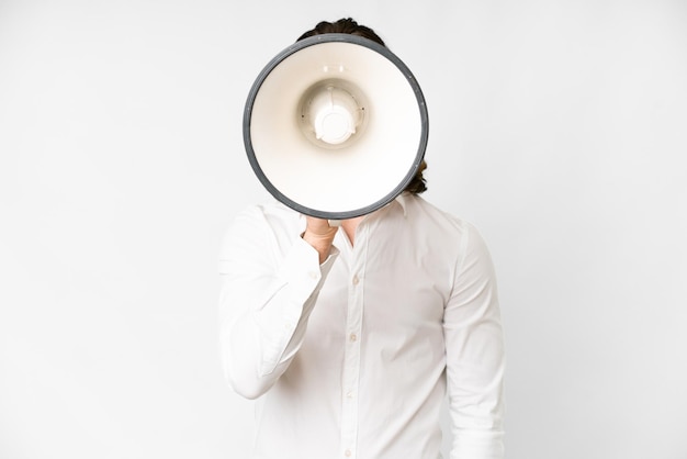 Young handsome man over isolated white background shouting through a megaphone to announce something