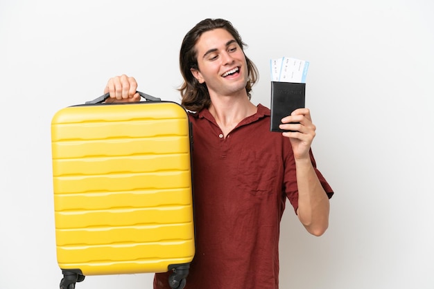 Young handsome man isolated on white background in vacation with suitcase and passport