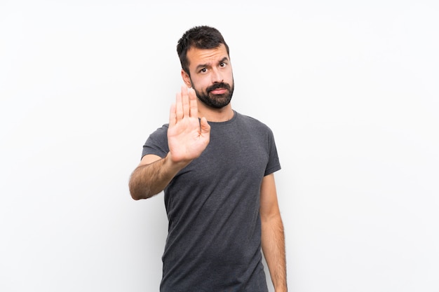 Young handsome man over isolated white wall making stop gesture