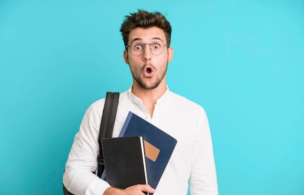 Young handsome man isolated with a bag and books university student concept