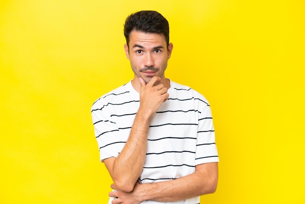 Young handsome man over isolated yellow background thinking