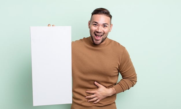 Young handsome man laughing out loud at some hilarious joke. empty canvas concept