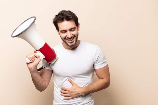 Young handsome man laughing out loud at some hilarious joke, feeling happy and cheerful, having fun