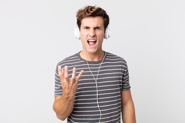 Young handsome man looking angry, annoyed and frustrated. listening music concept