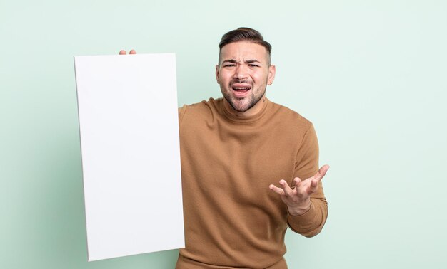 Young handsome man looking desperate, frustrated and stressed. empty canvas concept