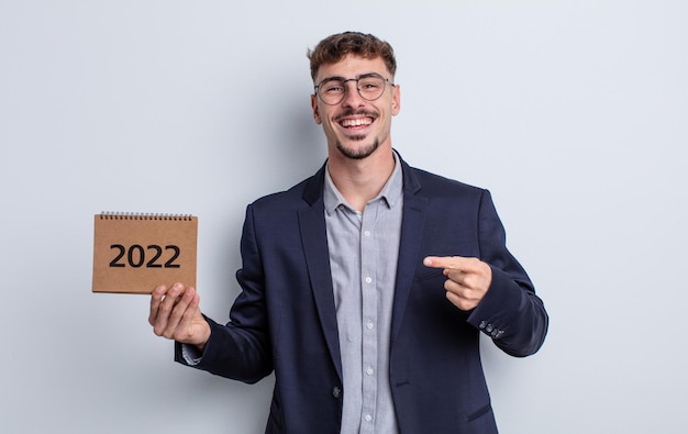 Young handsome man looking excited and surprised pointing to the side. calendar concept