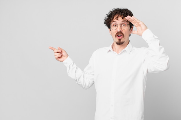 Young handsome man looking happy, astonished and surprised