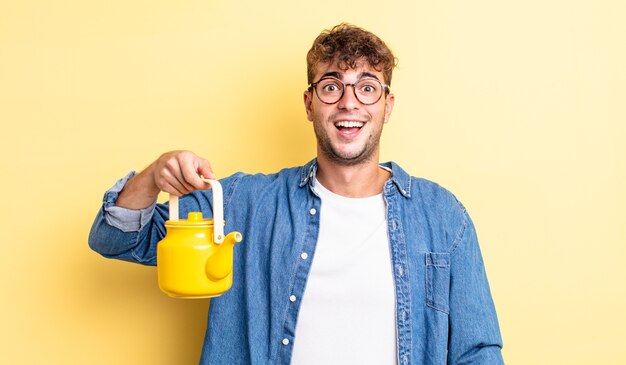 Young handsome man looking happy and pleasantly surprised.teapot concept