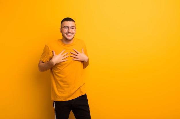 Young handsome man looking happy, surprised, proud and excited, pointing to self over wall