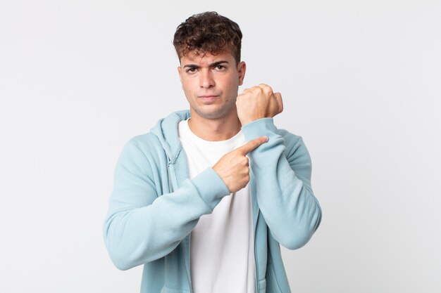 Young handsome man looking impatient and angry, pointing at watch, asking for punctuality, wants to be on time