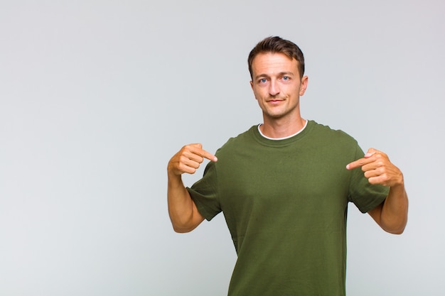 Young handsome man looking proud, positive and casual pointing to chest with both hands