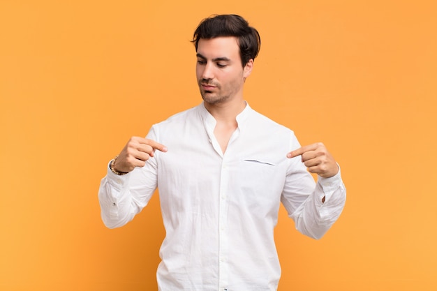 Young handsome man looking proud, positive and casual pointing to chest with both hands