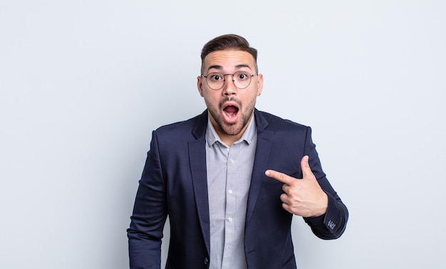 Young handsome man looking shocked and surprised with mouth wide open, pointing to self. businessman concept