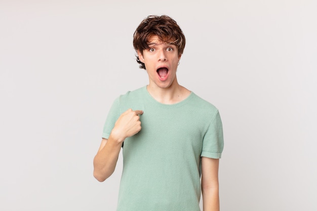 Young handsome man looking shocked and surprised with mouth wide open, pointing to self