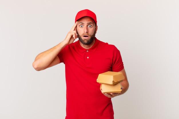 Young handsome man looking surprised, realizing a new thought, idea or concept burger delivering concept