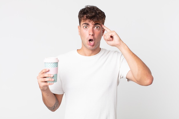 Young handsome man looking surprised, realizing a new thought, idea or concept and holding a take away coffee