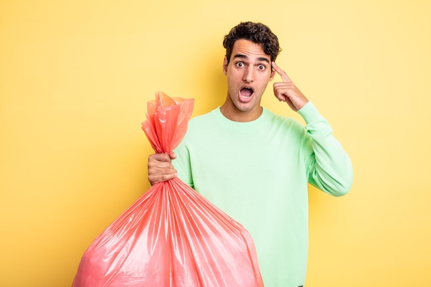 Young handsome man looking surprised, realizing a new thought, idea or concept. trash bag concept