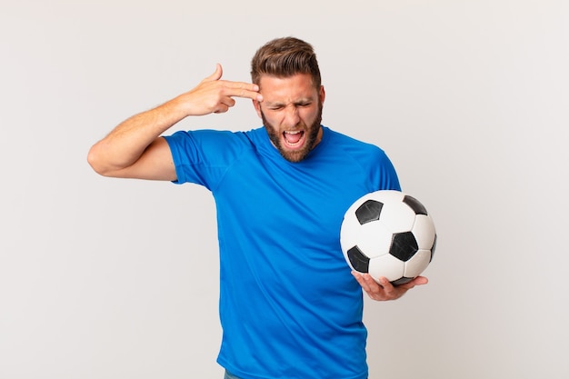 Young handsome man looking unhappy and stressed, suicide gesture making gun sign. soccer concept