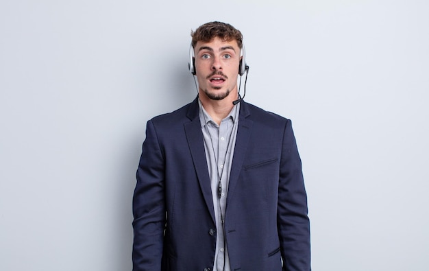 Young handsome man looking very shocked or surprised. telemarketer concept