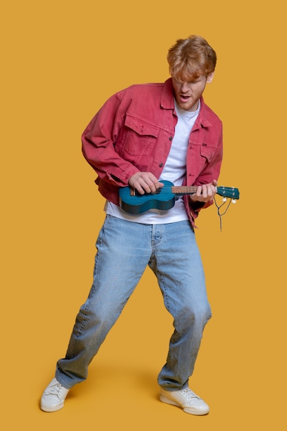 Young handsome man playing the ukulele