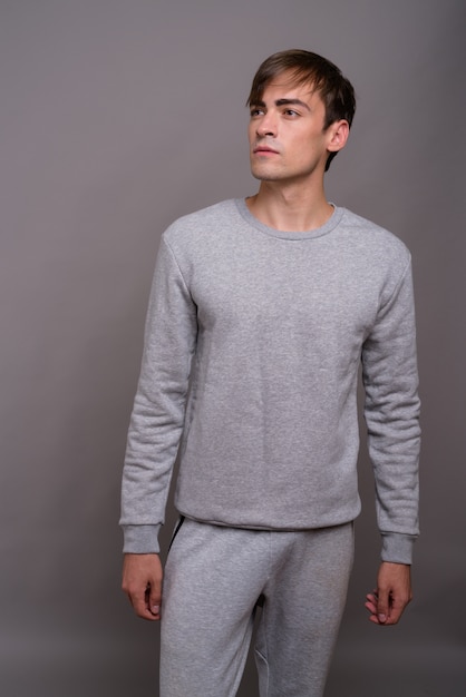 Young handsome man ready for gym against gray background