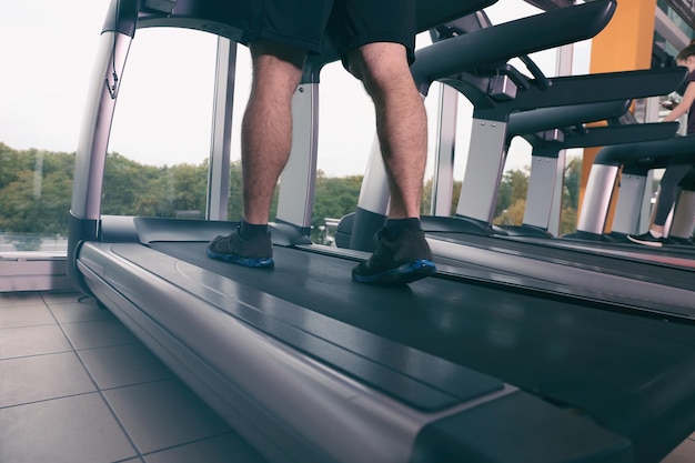 Young handsome man running on treadmill in gym